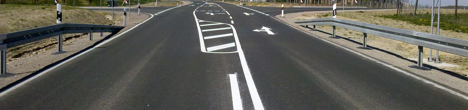 Frisch markierte Fahrbahn mit weißen Leitlinien und Leitpfosten